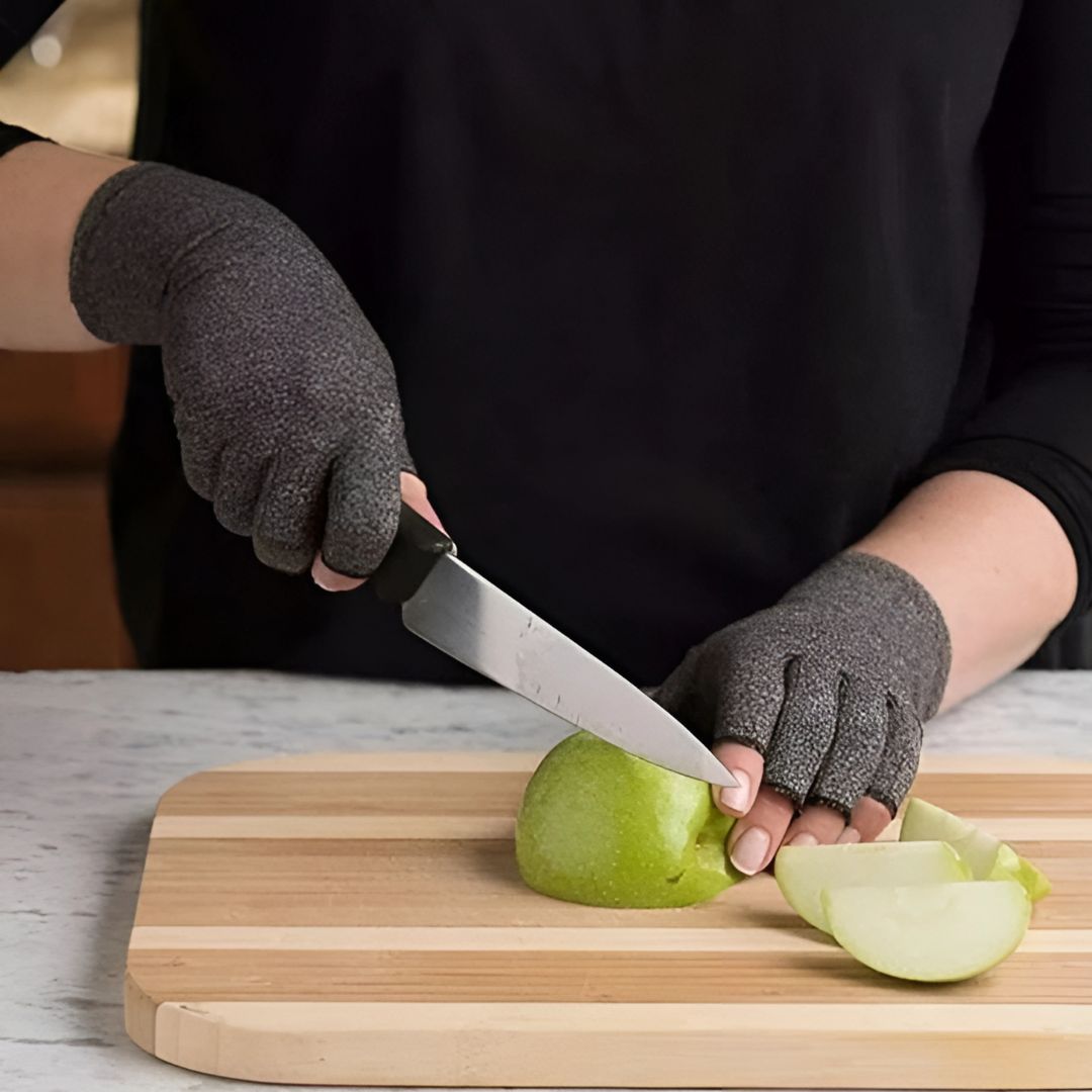 Person som bär grå termohandskar med öppna fingrar medan de skär ett äpple på en skärbräda