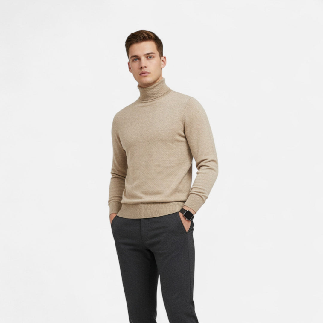 Man som bär beige höghalssweater och mörka byxor