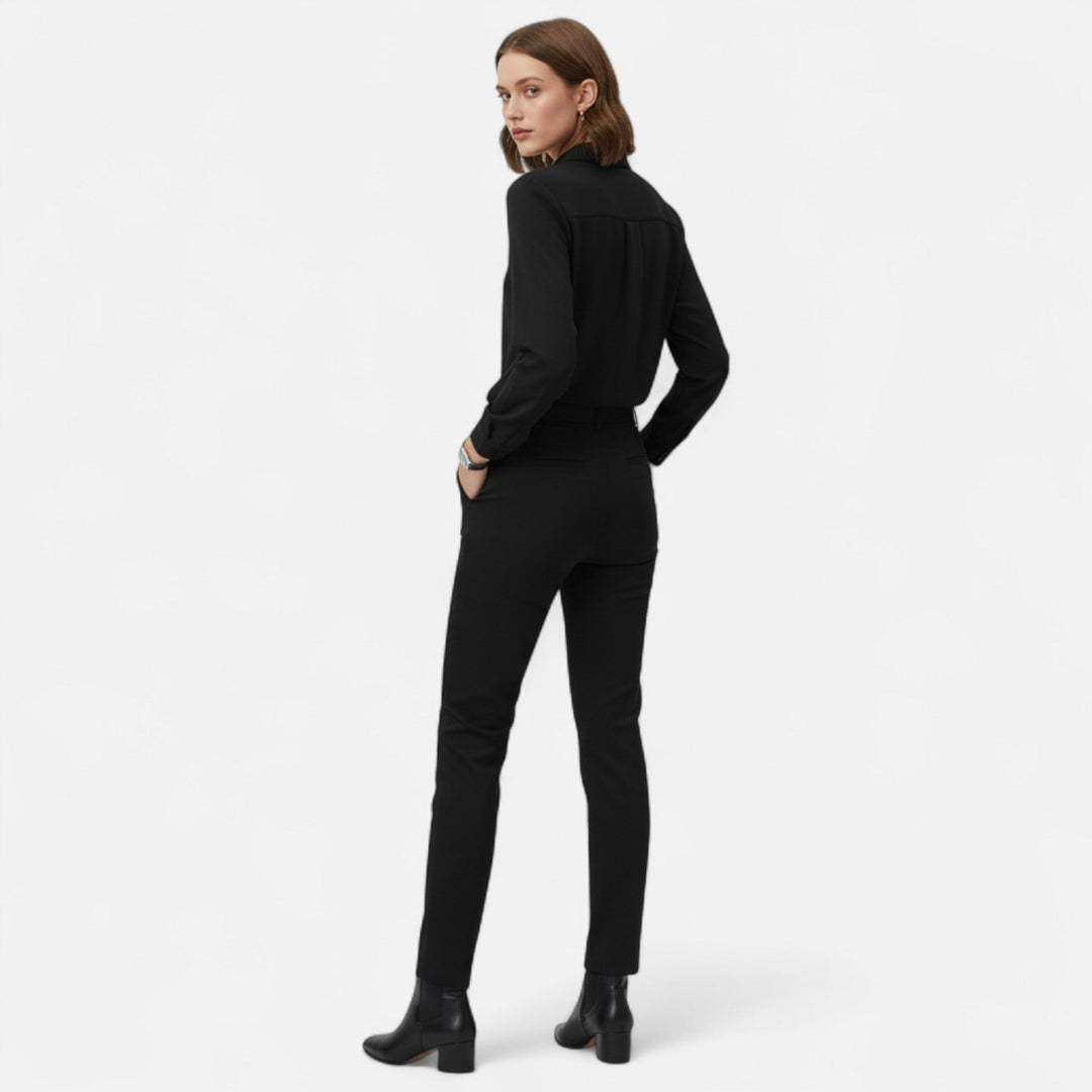 Bakifrån på modell i svart elegant blus och matchande byxor