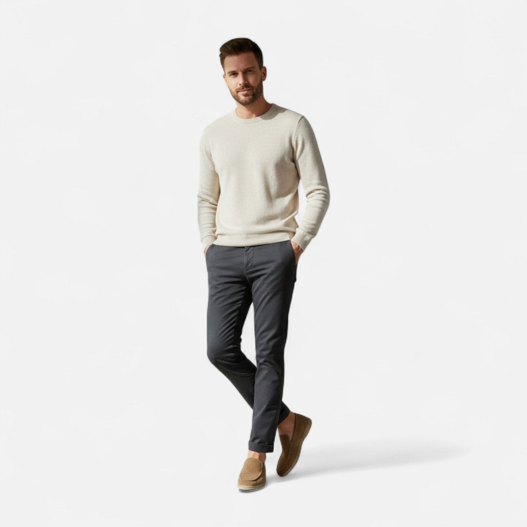 Man som står i helfigur klädd i stickad tröja och ljusbruna loafers