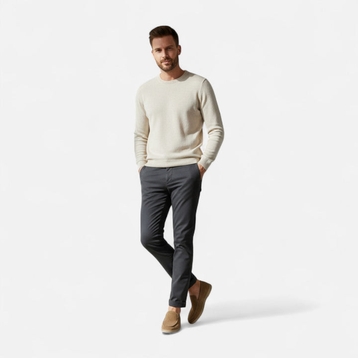 Man som står i helfigur klädd i stickad tröja och ljusbruna loafers
