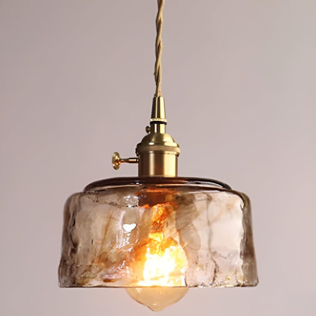 Närbild på bärnstensfärgad glastaklampa med vridknapp