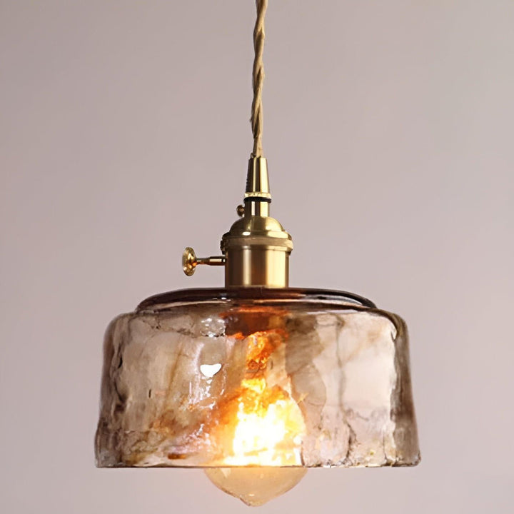 Närbild på bärnstensfärgad glastaklampa med vridknapp