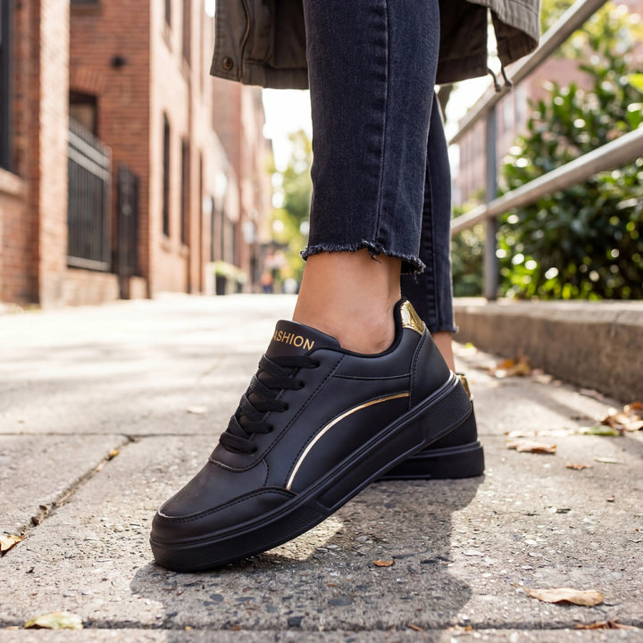 Svart dam sneaker med gulddetaljer utomhus på gata