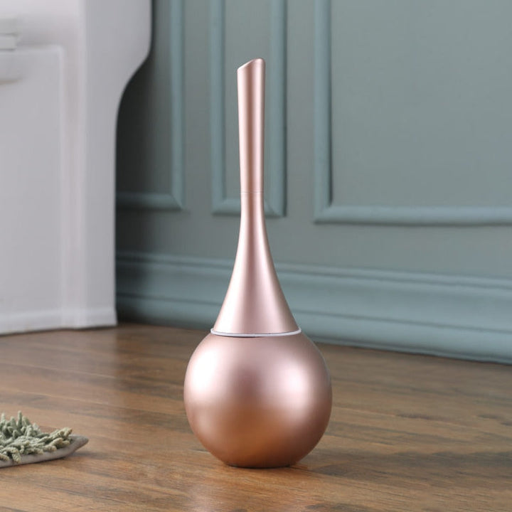 Elegant toalettborste i kopparfinish stående i ett badrum
