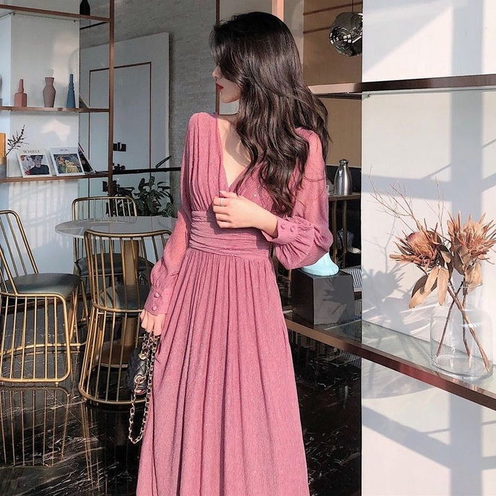 Sida av kvinna som bär den eleganta rosa maxiklänningen i ett ljust rum