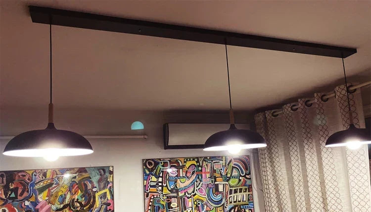 Svart avlång takplatta med tre hängande lampor installerad i ett hem