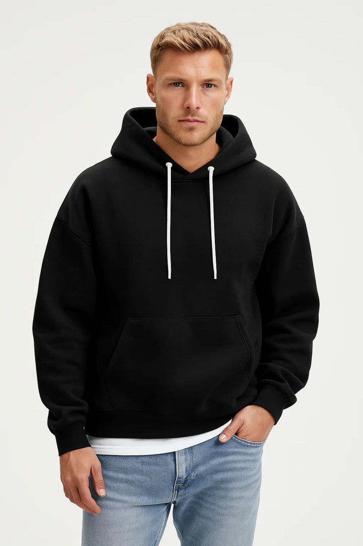 Man i svart hoodie med huva och vit dragsko mot ljus bakgrund