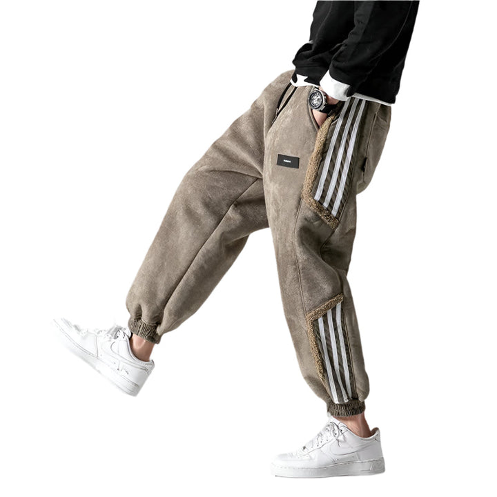 Man som bär khaki-färgade herrjoggers med sidosträckning tillsammans med vita sneakers