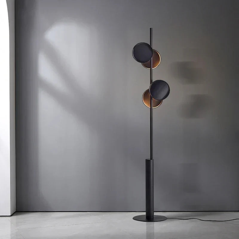 Typografi Golvlampa i mattsvart metall med nordisk minimalistisk design stående mot grå vägg
