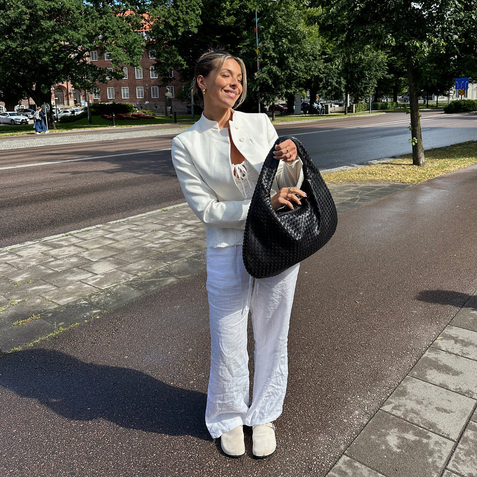 Närbild på det flätade mönstret i rött och svart på elegant damväska