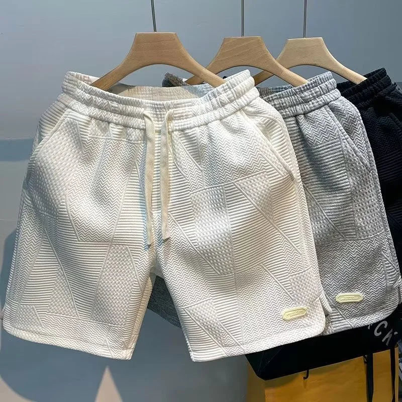 Herrshorts med fiskbensmönster i vitt, grått och svart hängande på galgar