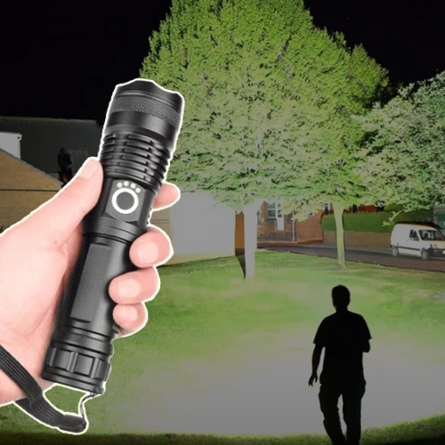 Person håller en svart kraftfull LED-ficklampa som lyser upp mörkret utomhus