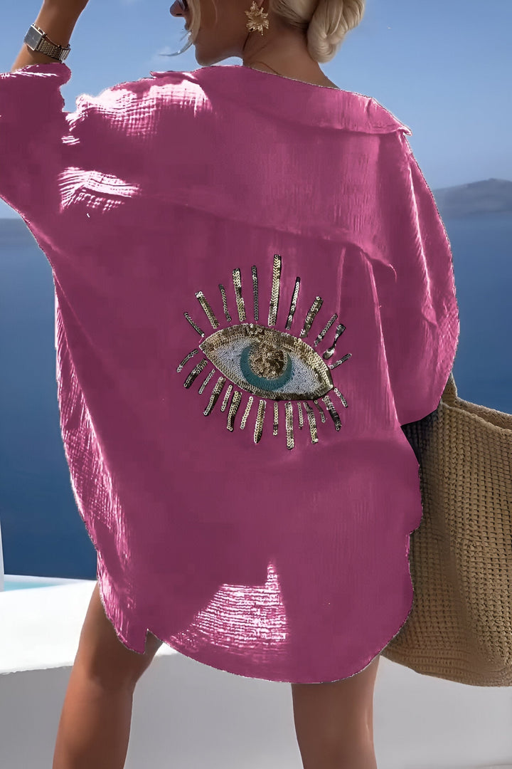 Modell som bär den moderiktiga evil eye-blusen för varma sommardagar