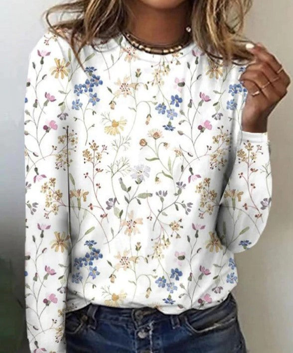 Närbild på mönstrad damtröja med blomdetaljer på vit botten