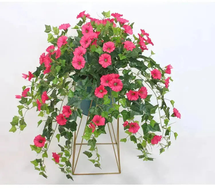 Rosa konstgjorda blommor i kruka på guldfärgat ställ