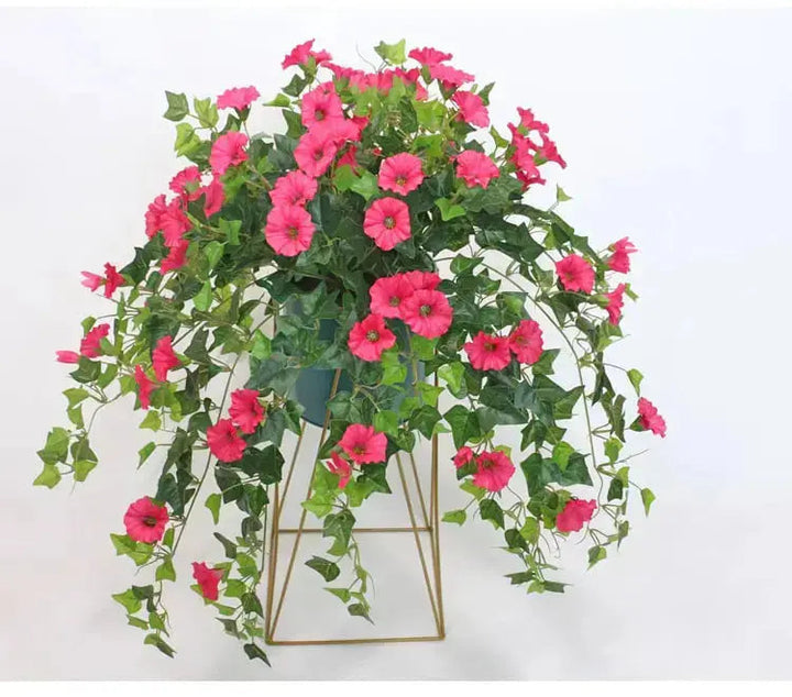 Rosa konstgjorda blommor i kruka på guldfärgat ställ