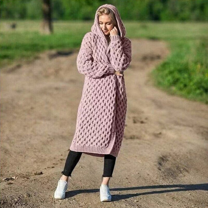 Kvinna bär en rosa lång stickad damkofta med huva utomhus