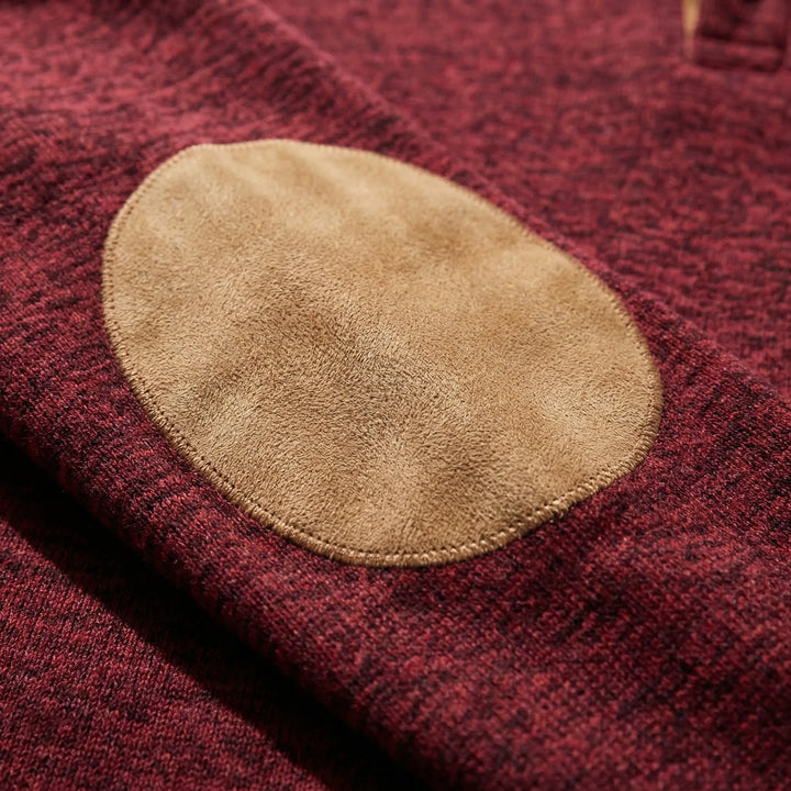 Närbild på texturerad armbågslapp i kontrastfärg på tröjan