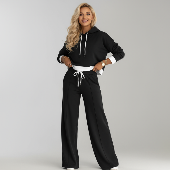 Kvinna i svart tvådelad loungeoutfit med luvtröja och vida byxor [[lstfy-media:1]]