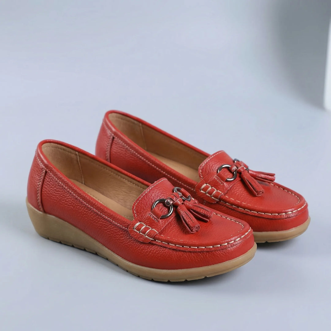 Närbild på eleganta toffsar och metallspänne på damloafer