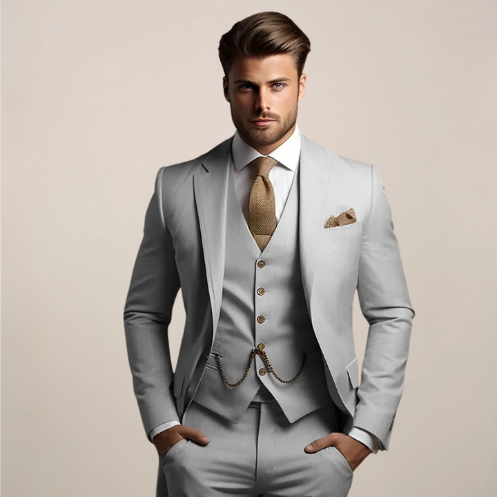 Elegant man i ljusgrå skräddarsydd kostym med väst och slips