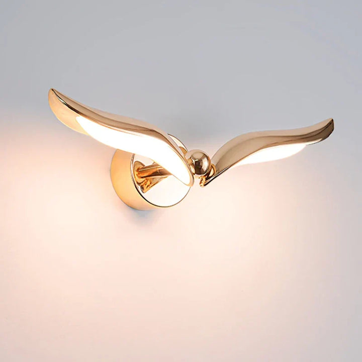 GoldenHorizon gyllene måsformad vägglampa tänd mot ljus vägg