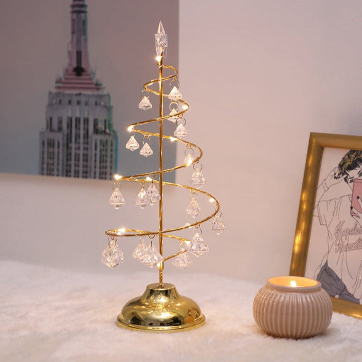 Helhetsbild av en guldfärgad kristalljulgran som står upplyst på ett bord