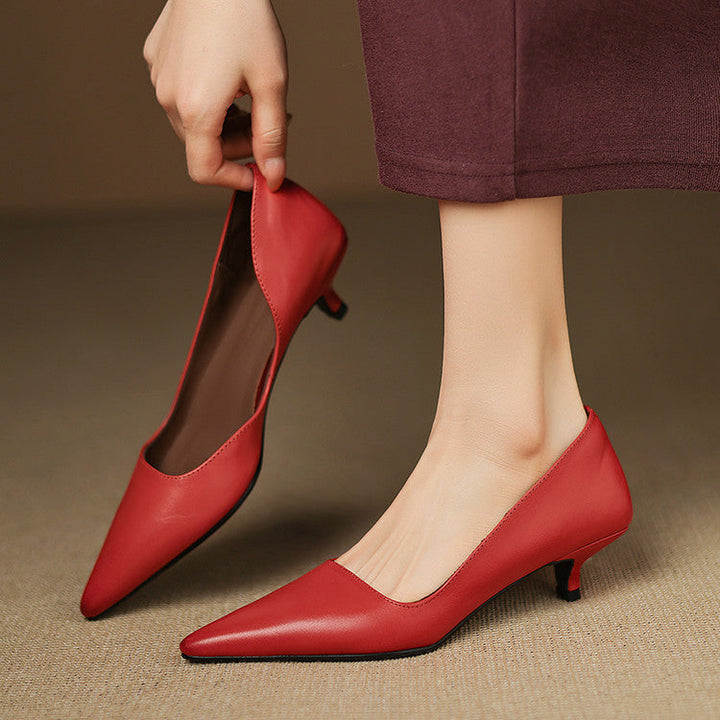 Röda pumps med kitten heel som hålls upp mot benet