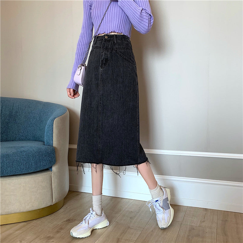 Dam i svartgrå denimkjol med hög midja och asymmetrisk kant
