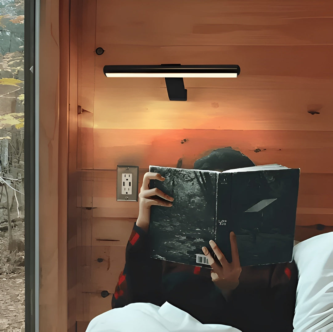 Person som läser bok i sängen med trådlös LED-vägglampa som belysning