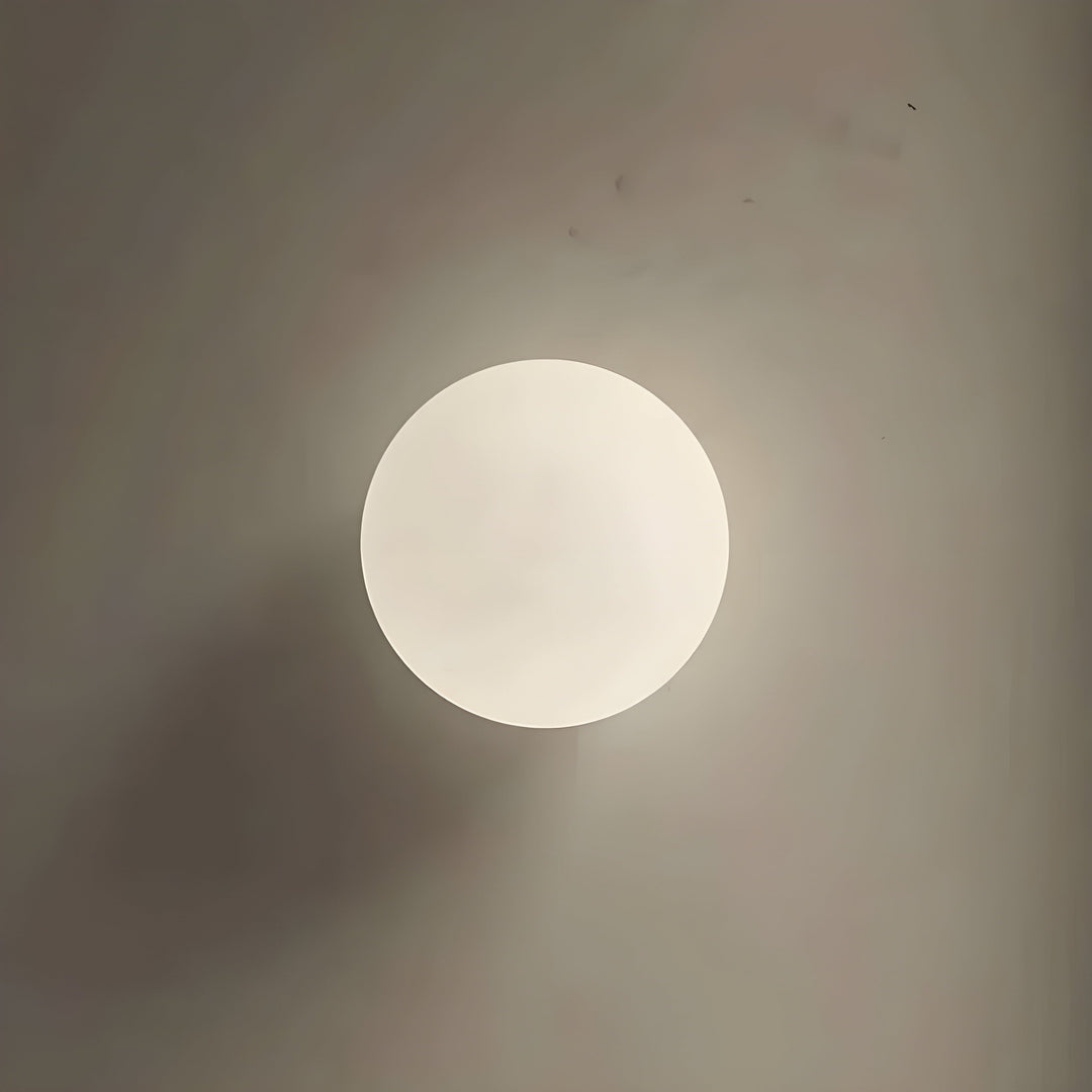 Modern rund LED-vägglampa i glas monterad i ett elegant vardagsrum
