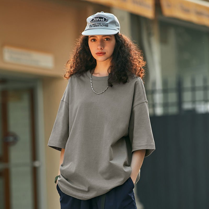 Kvinna i grå oversize t-shirt och keps utomhus