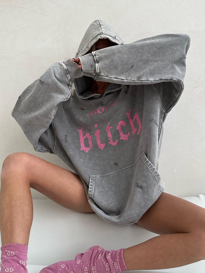 Närbild på kvinna som döljer ansiktet i luvan på en grå hoodie