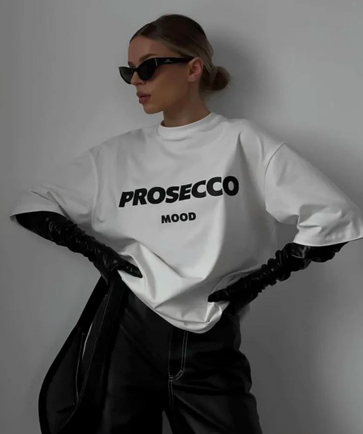 Modell i vit oversized t-shirt med svarta solglasögon och handskar