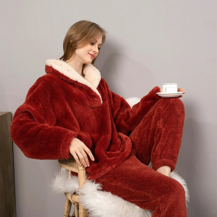 Kvinna i vinröda Paloma fleece-loungekläder som sitter bekvämt och dricker kaffe