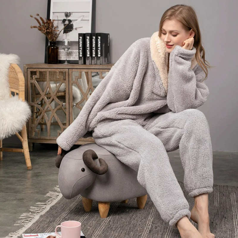 Kvinna i grå Paloma loungekläder av fleece sittande på en liten dekorativ fårpall