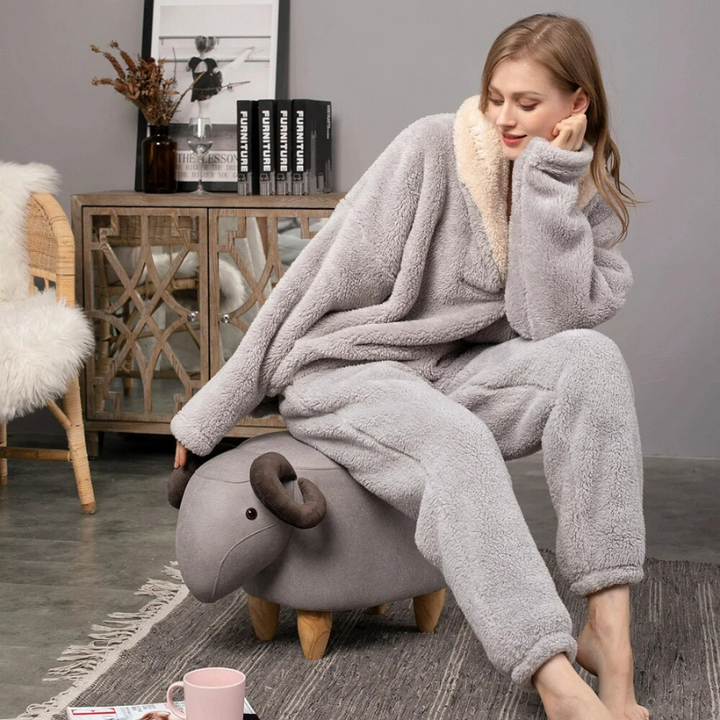 Kvinna i grå Paloma loungekläder av fleece sittande på en liten dekorativ fårpall