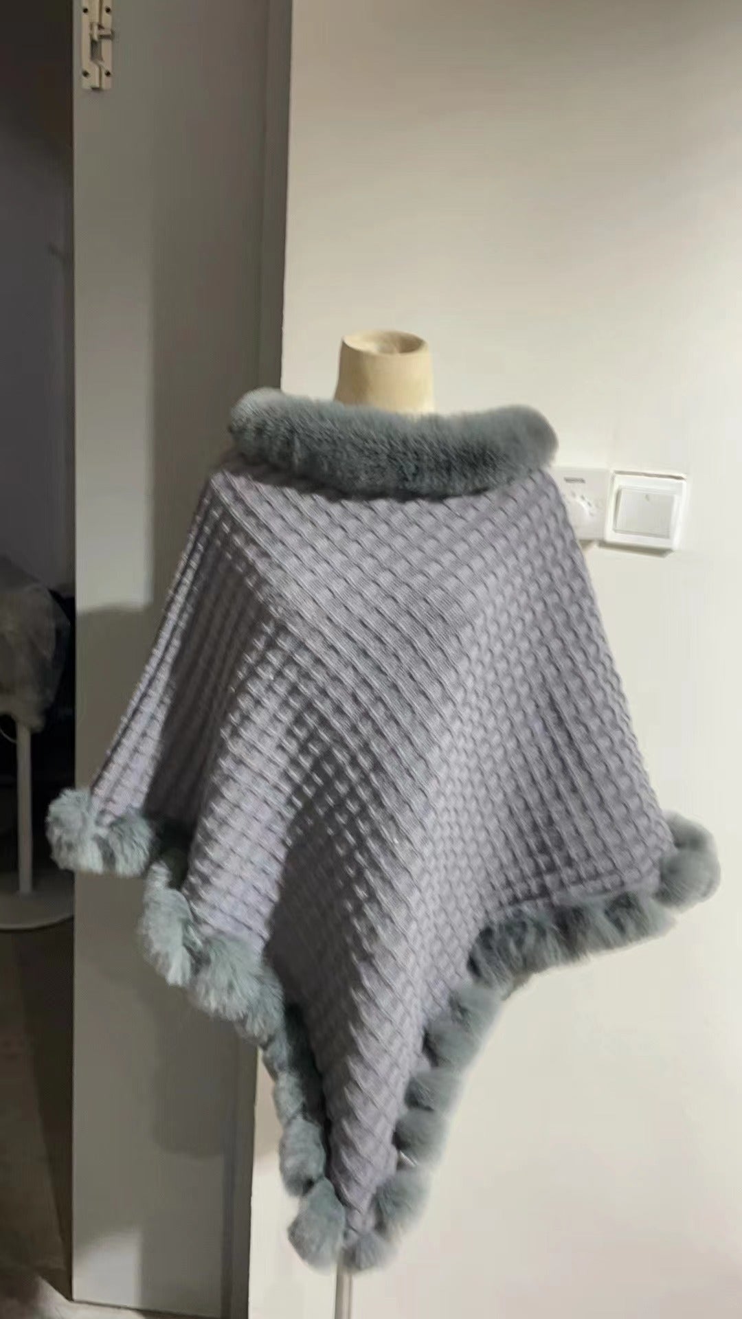 Trendig ytterklädsel för damer i form av en stickad poncho