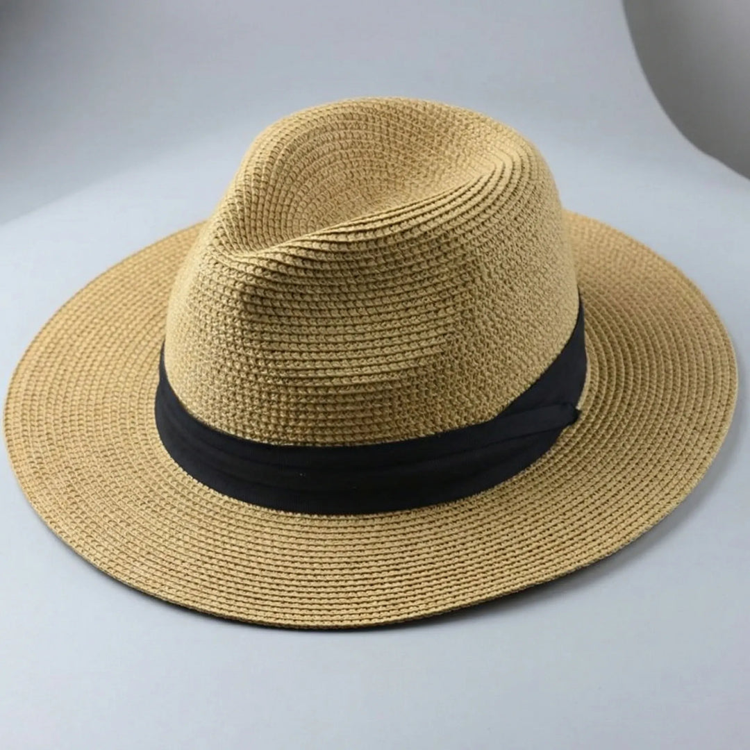 Närbild på en elegant beige fedorahatt med svart hattband mot ljus bakgrund