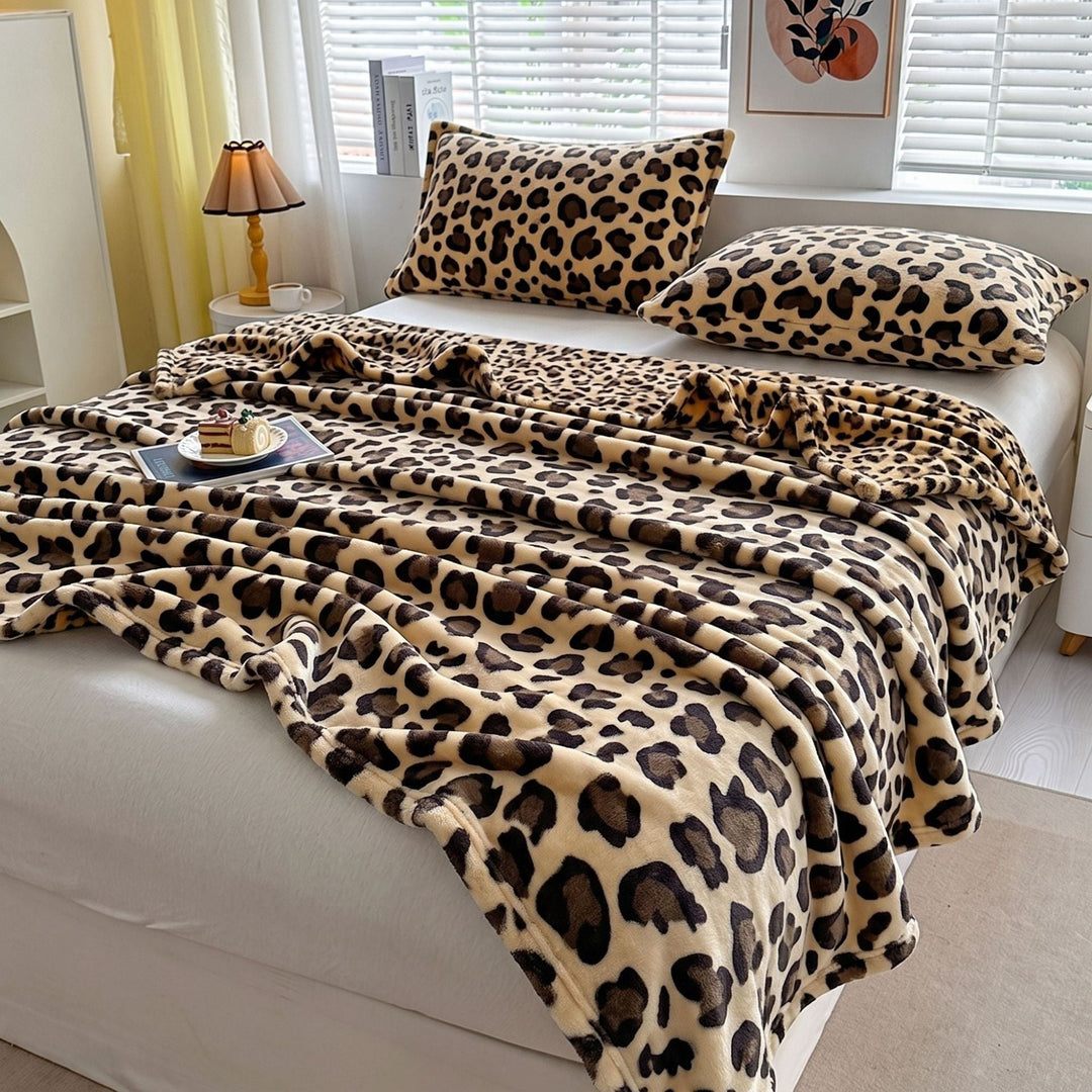 Leopardsmönstrad pläd utbredd på en säng med matchande kuddar