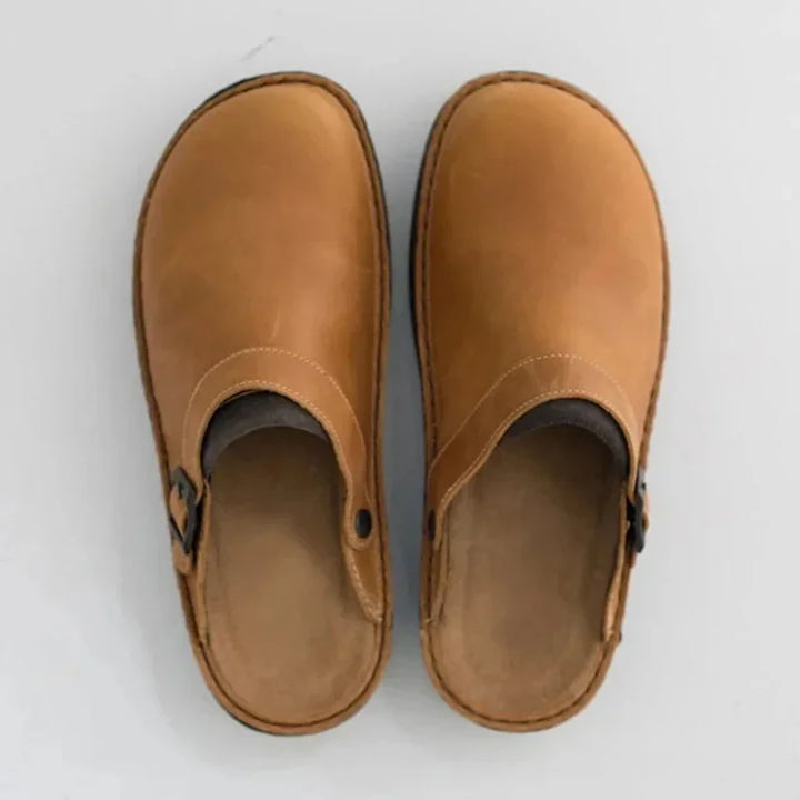 Brunt läder på bekväma slip-on herrskor med dekorativt spänne, visat från sidan