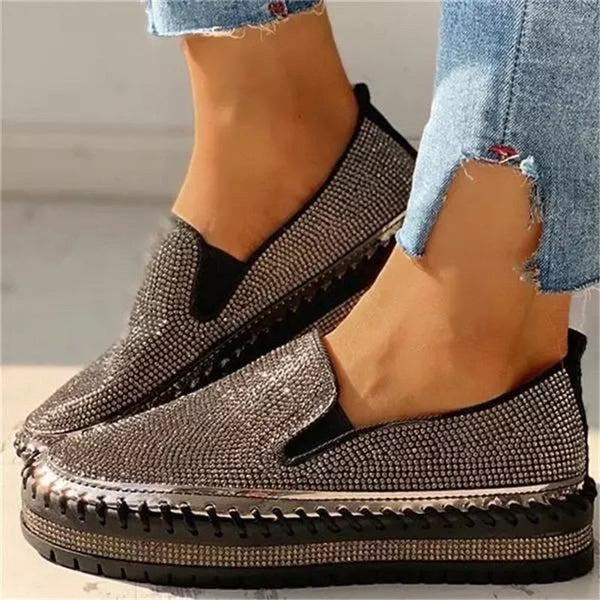 Närbild på svarta glittrande slip-on-skor för damer