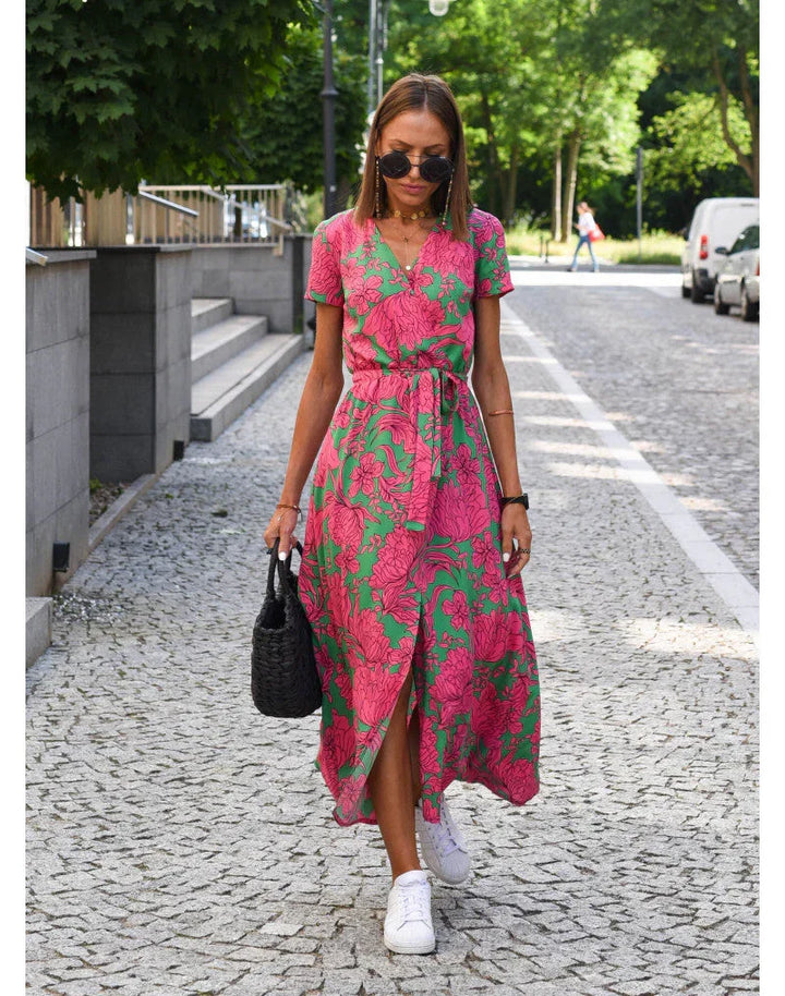 Kvinna i rosa och grön blommig sommarklänning utomhus