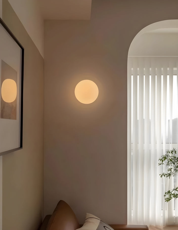 Inredningsdetalj med rund LED-vägglampa placerad ovanför soffa