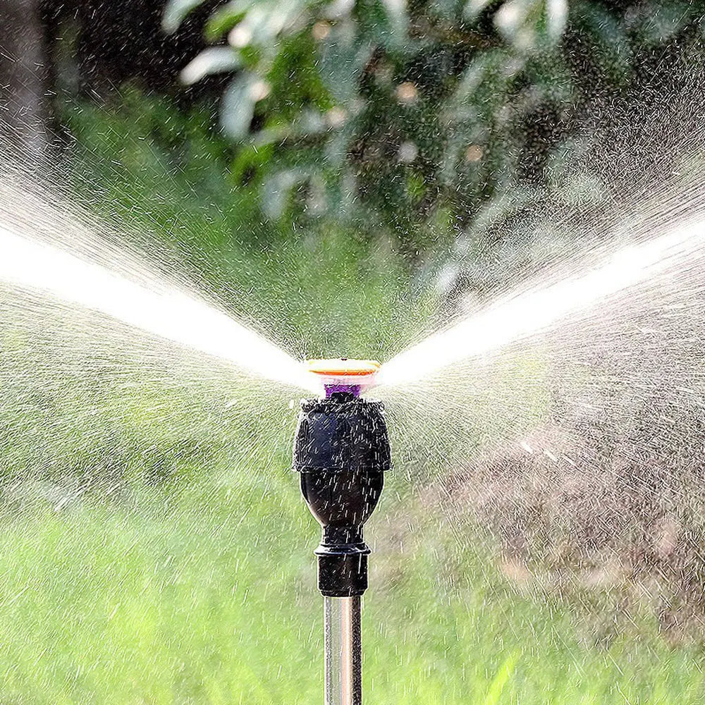 Effektiv vattensprinkler i aktion som bevattnar gräsmattan i stora cirklar