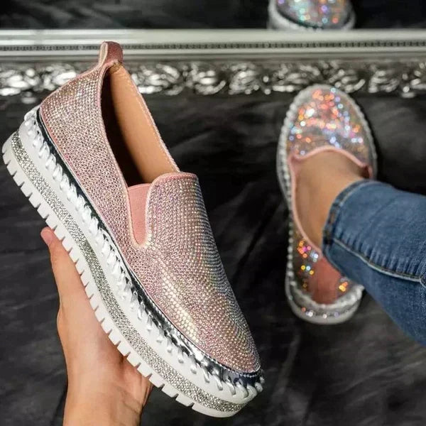 Rosa glittrande slip-on-skor som hålls i handen