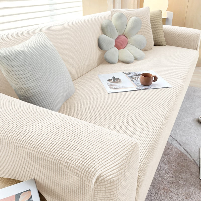 Beige texturerat stretchsofföverdrag på en modern soffa