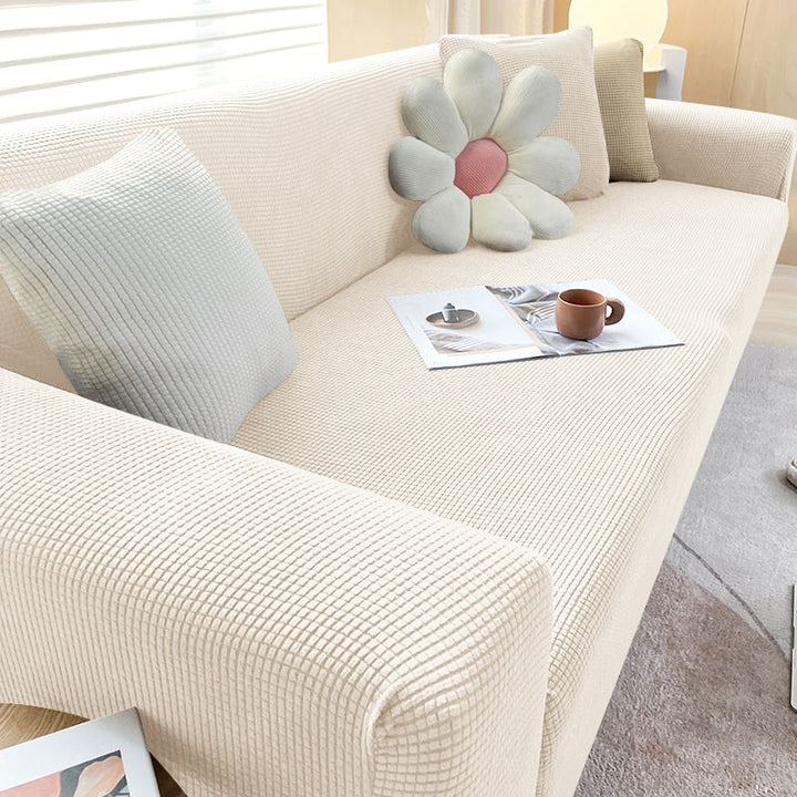 Beige texturerat stretchsofföverdrag på en modern soffa