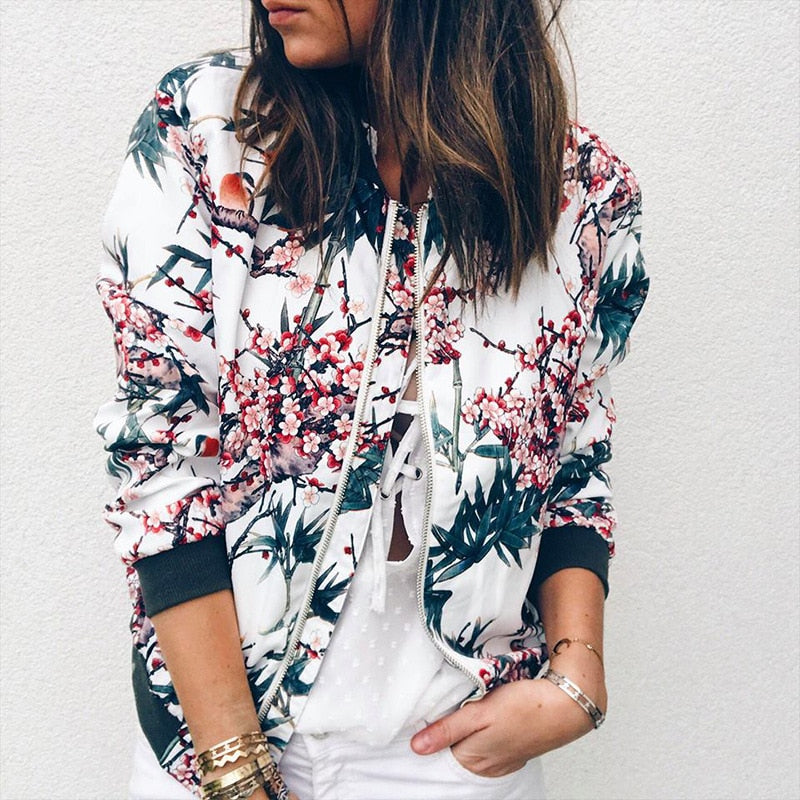 Närbild på dam i vit blommig bomberjacka med dekorativt mönster